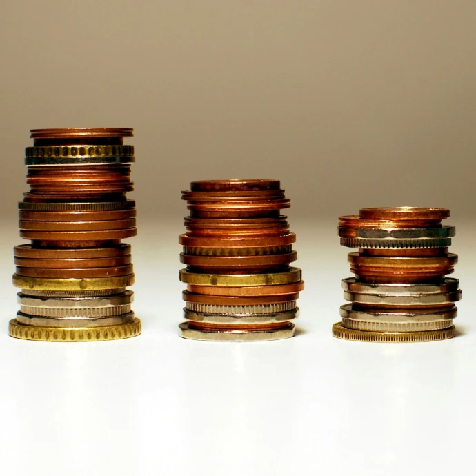 Tres pilas de monedas ordenadas de mayor a menor altura de izquierda a derecha representando beneficio decreciente.